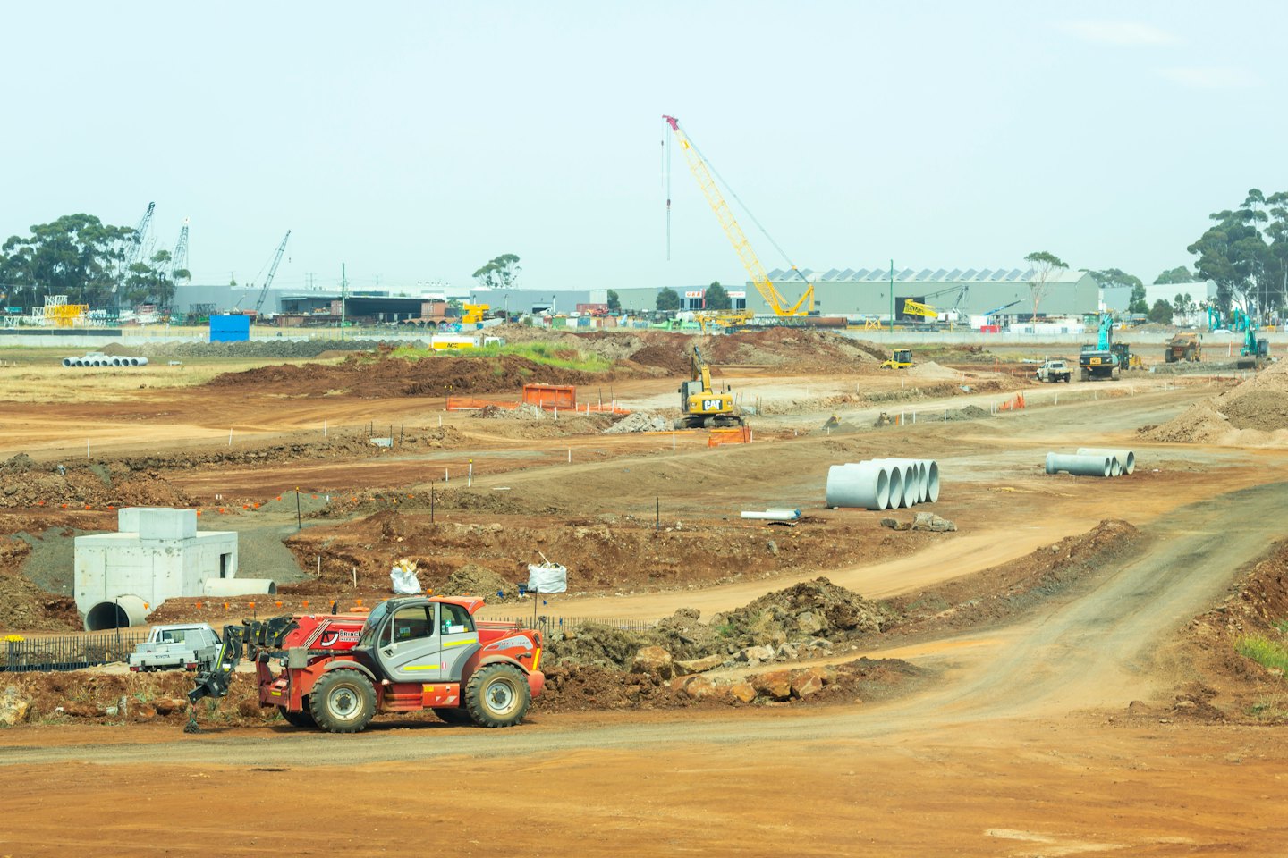 Construction site with heavy machinery and earthworks under an overcast sky.